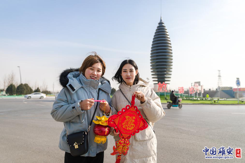 农历腊月二十三，北方“小年”至，过年模式正式开启。雄安新区容城县容和塔前，群众在镜头前展示刚刚购买的中国结、红灯笼。中国雄安官网记者马梦迪 摄