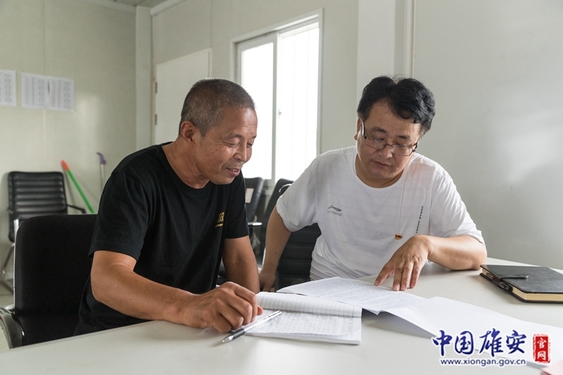 在大张堡村综合服务站内，摆放着几张办公桌和几张简易床。工作认真、兢兢业业是同事对王占忠的评价。下班后，王占忠还会与其他征迁村的驻村党员干部、村“两委”干部进行交流探讨，借鉴他们的经验。图为王占忠与大张堡村原村委会主任交流学习。中国雄安官网记者牛思佳 摄